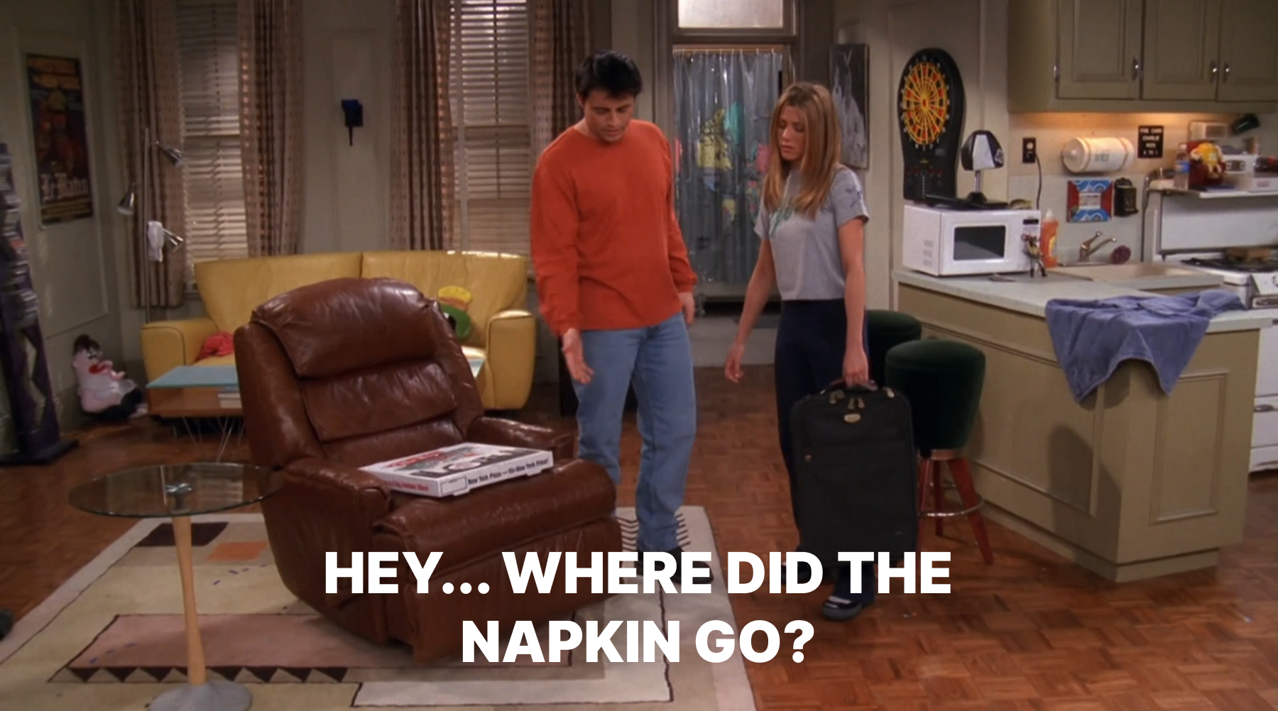 A scene from the TV show Friends. Joey, wearing a red sweater and jeans, gestures toward an empty recliner while Rachel, holding a suitcase, looks on. Large caption text at the bottom says: “HEY… WHERE DID THE NAPKIN GO?”